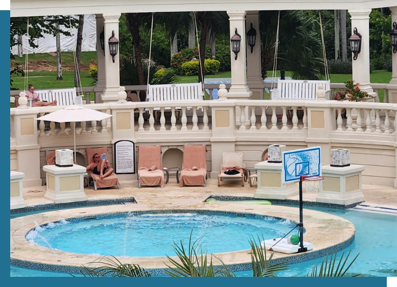 A pool with chairs and umbrellas in the background.